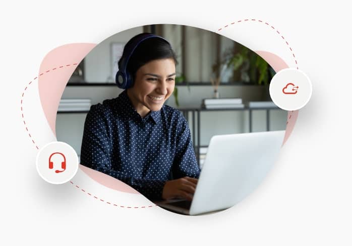 A smiling female employee seated in front of the laptop wearing wireless earphones has a web conference with colleagues